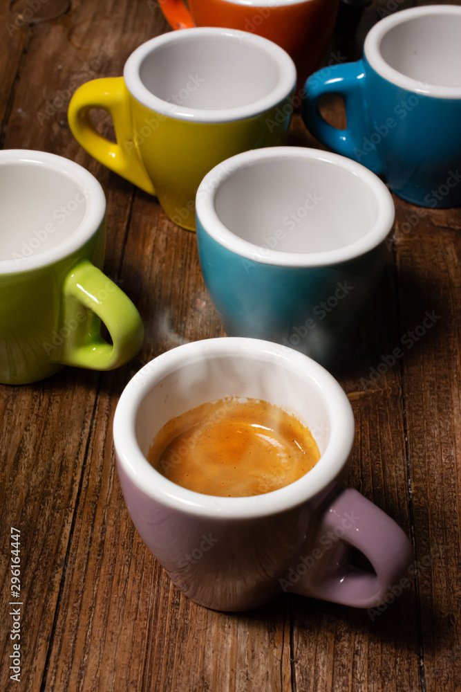 Various colored coffee cups and a cup with steaming espresso coffee Various colored coffee cups and a cup with steaming espresso coffee