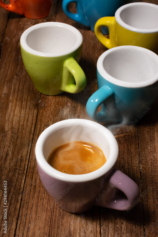 Various colored coffee cups and a cup with steaming espresso coffee Various colored coffee cups and a cup with steaming espresso coffee