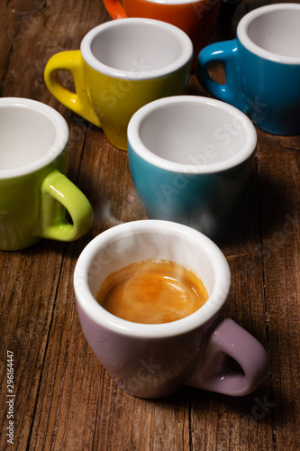 Various colored coffee cups and a cup with steaming espresso coffee