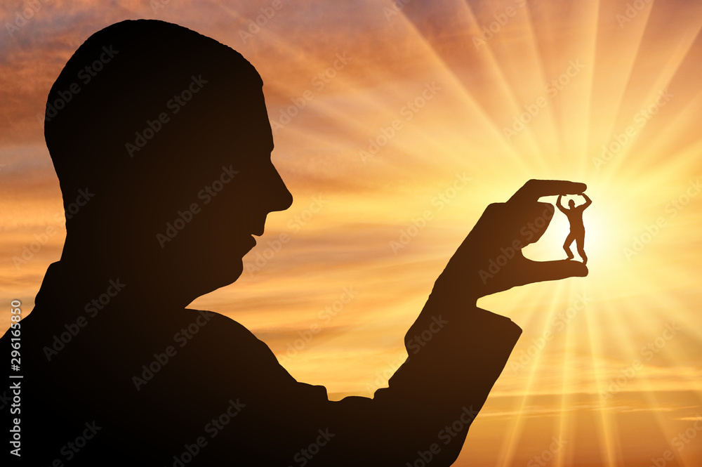 Bullying concept. Silhouette of a man holds a man between his fingers Bullying concept. Silhouette of a man holds a man between his fingers