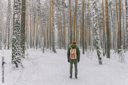 A young man with a red backpack walks in a snowy forest. The silence of the winter forest. Winter fairy tale. New year's eve mood. The trees are covered with snow.