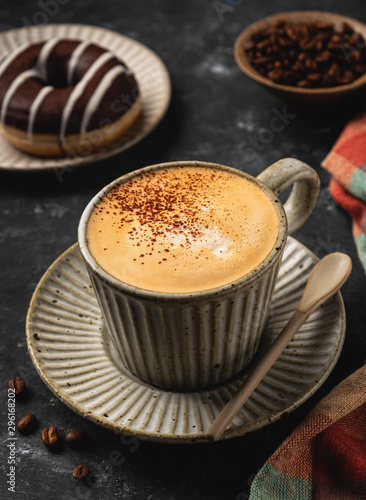 coffee in a cup with a donut and coffee grains, dark background