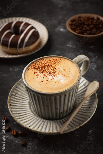 coffee in a cup with a donut and coffee grains, dark background