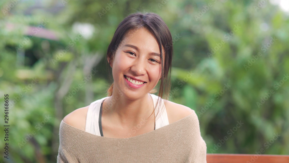 Asian woman feeling happy smiling and looking to camera while relax on table in garden at home in the morning. Lifestyle women relax at home concept. - obrazy, fototapety, plakaty 