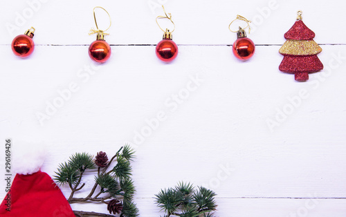 Christmas background top view. Christmas decorations around the perimeter of red and gold. Coniferous branches with Christmas toys on a background of a white wooden board. New Year 202