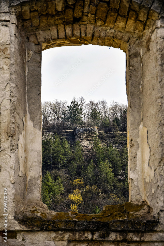 View of the mountain landscape through the window of an old dilapidated synagogue. Old stonework. Mountains, forest, ruins. Rashkov, Moldova.