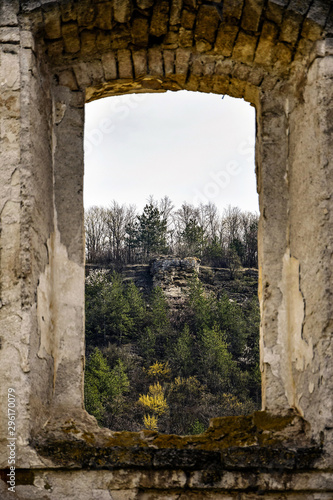 View of the mountain landscape through the window of an old dilapidated synagogue. Old stonework. Mountains, forest, ruins. Rashkov, Moldova.