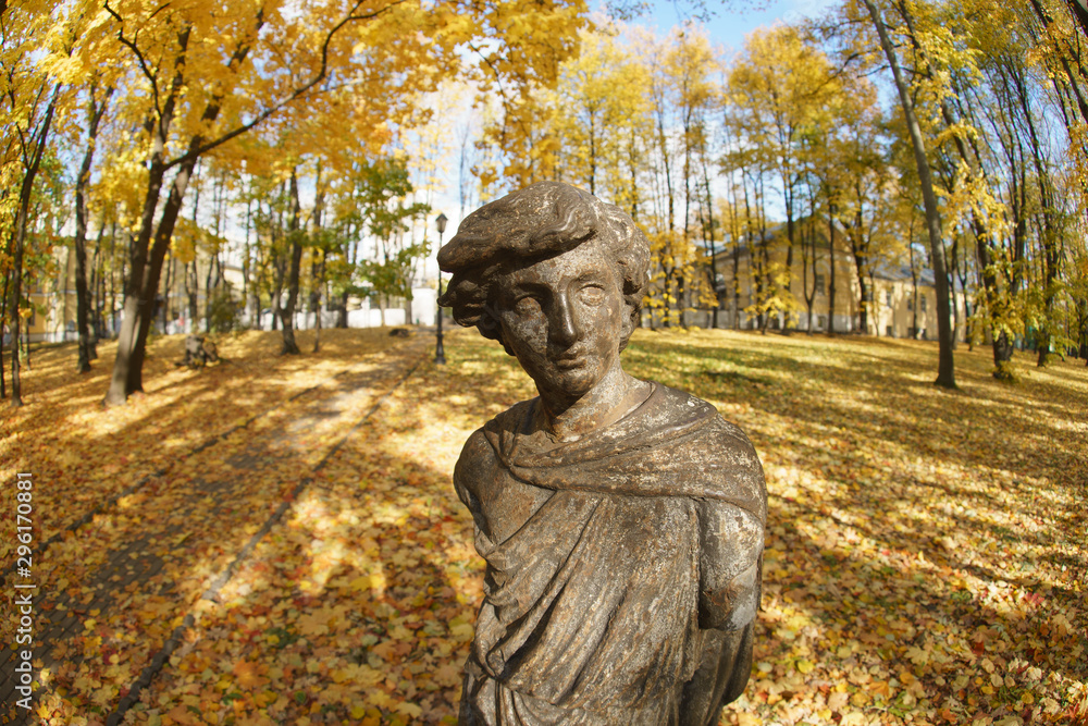 Photography of boy statue among fallen yellow maple leaves in the autumn city park. The Usachev - Naydenovs Manor / High Mountains. Fish Eye lens.