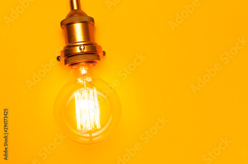 Vintage fashionable edison lamp on bright yellow background. Top view flat lay copy space. Creative idea concept, designer lamp, modern interior item. Lighting, electricity, background with lamp
