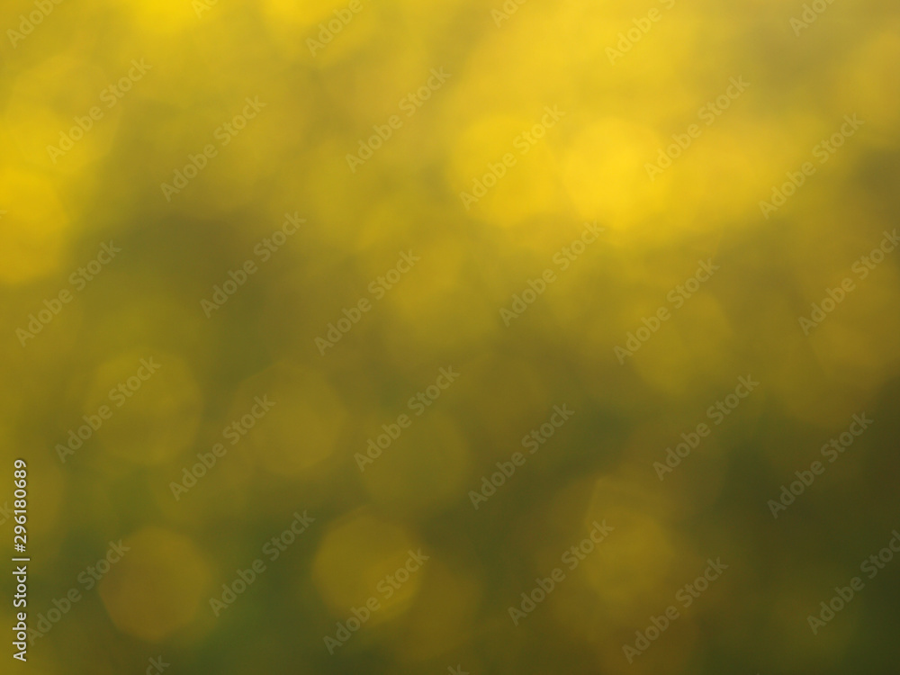 Green and yellow colored abstract light background.Natural outdoors bokeh backdrop in green and yellow tones with sun rays. Abstract blur spring meadow pattern.