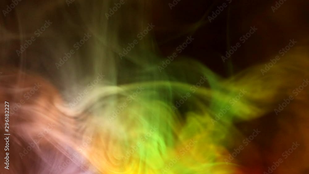 Curly creeping puffs of smoke on a dark background, illuminated by light with different colors. Curly creeping puffs of smoke on a dark background, illuminated by light with different colors.