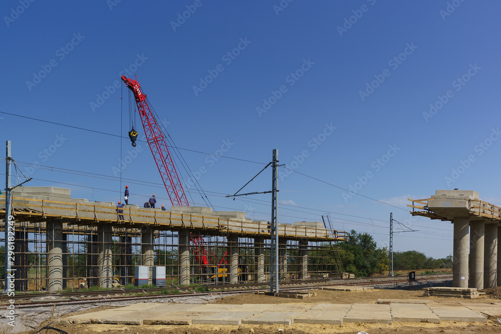 Workers at the construction of an elevated bridge crossing the railway tracks. Works crane. Sunny day Workers at the construction of an elevated bridge crossing the railway tracks. Works crane. Sunny day