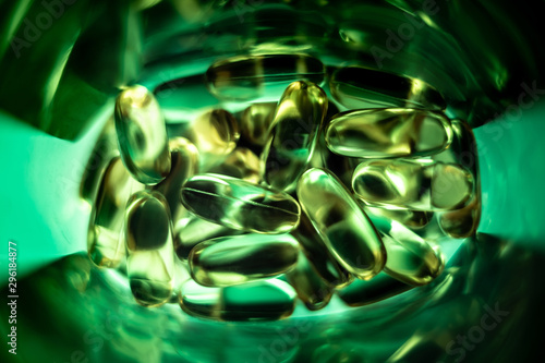 green pills in a plastic bottle. vitamin e and fish oil