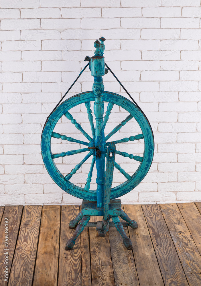 vintage spindle, spinning wheel, wooden floor and white brick wall
