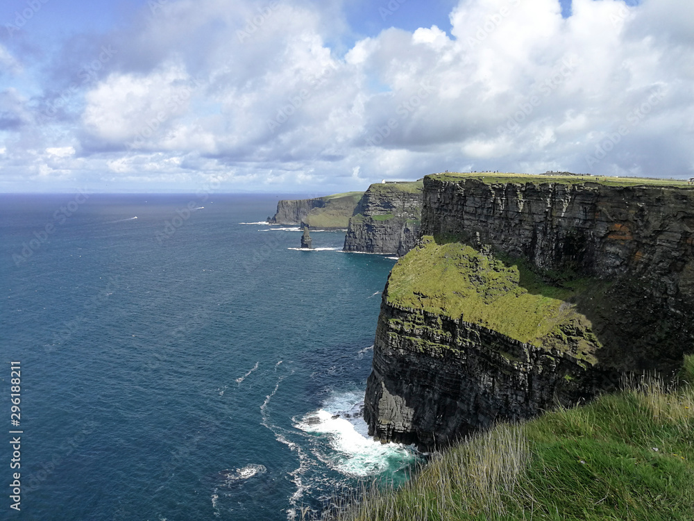 View of the famous Cliffs of Moher, Ireland, taken on a sunny summer day showing blue sky, green grass and ocean