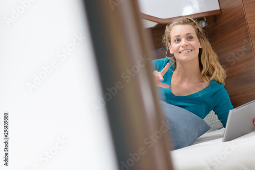 cheerful woman with tablet on bed