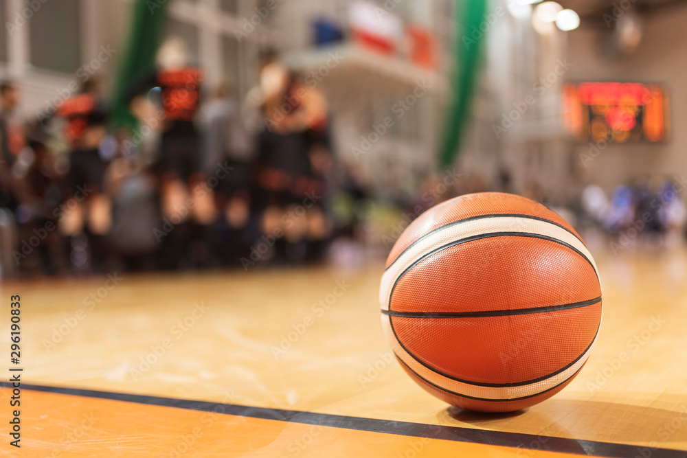 baketball ball on the parquet with team in the background baketball ball on the parquet with team in the background