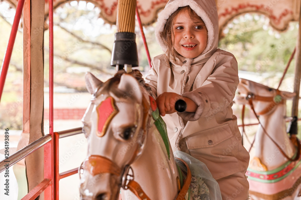 The girl in bright clothes rides on the carousel on a holiday. Happy baby is having fun The girl in bright clothes rides on the carousel on a holiday. Happy baby is having fun