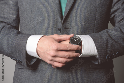 Businessman is checking a time on his wrist watch close up.