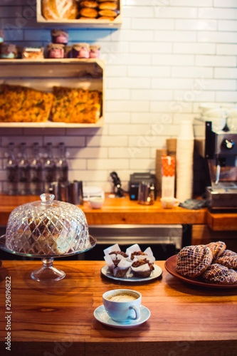 Taza de cafe en cafetería rodeado de pan dulce