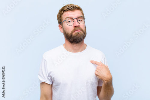 Fotografía young blonde adult man feeling confused, puzzled and insecure, pointing to self