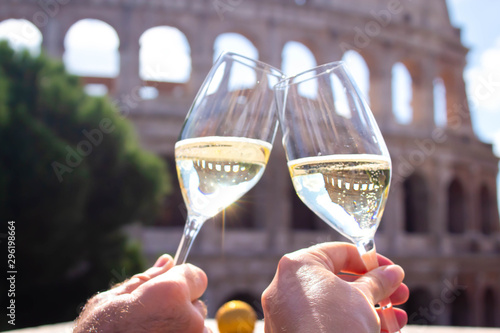 Canvas Print two hands hold a glass of champagne against the backdrop of the Coliseum