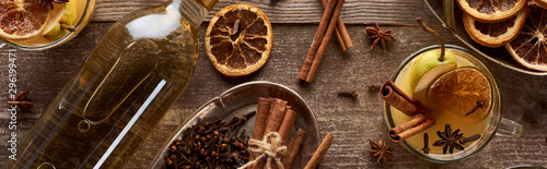 top view of warm pear mulled wine with spices and dried citrus on wooden table, panoramic shot