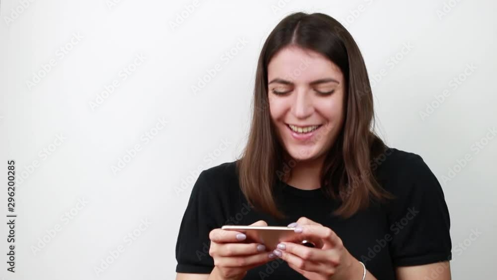 Brown-haired woman looks at the phone video and laughs.Girl with dark brown hair. Brown-haired woman looks at the phone video and laughs.Girl with dark brown hair.