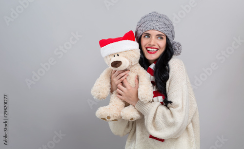 Young woman holding a teddy bear on a gray background
