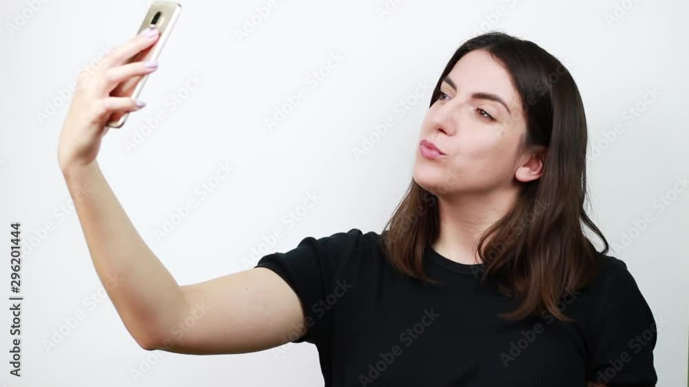 Brown-haired woman makes selfies. Admiring himself in the phone. White background Brown-haired woman makes selfies. Admiring himself in the phone. White background