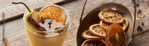 pear mulled wine with spices and dried citrus on wooden table, panoramic shot