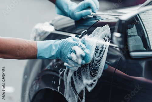 cropped view of car cleaner washing car with sponge and detergent photo