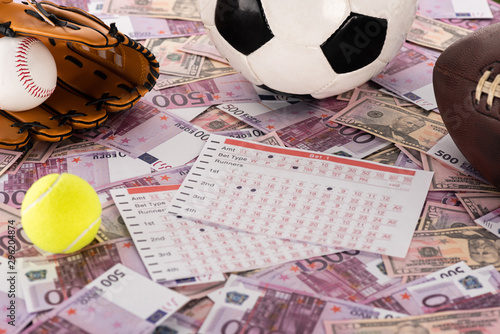 Fototapeta baseball glove and ball, soccer, tennis and rugby balls near betting lists on eu