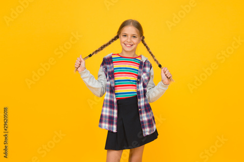 Preteen girl colorful clothes. Childrens shop store mall. Adorable girl beautiful face. Hairdresser salon. Little girl. Small child with cute braids hairstyle on yellow background. Child care concept
