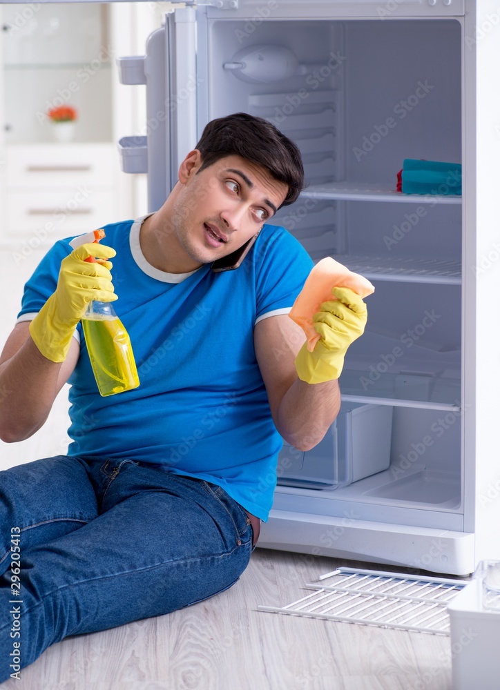 Man cleaning fridge in hygiene concept Man cleaning fridge in hygiene concept
