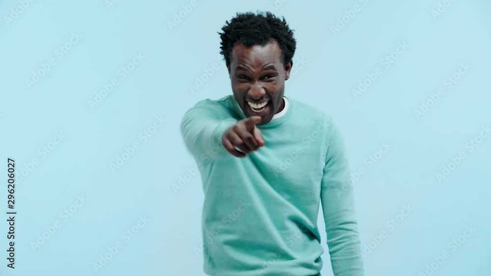 laughing african american man pointing with finger isolated on blue laughing african american man pointing with finger isolated on blue