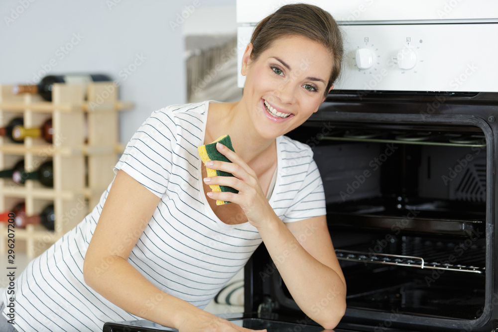 a happy woman cleaning oven