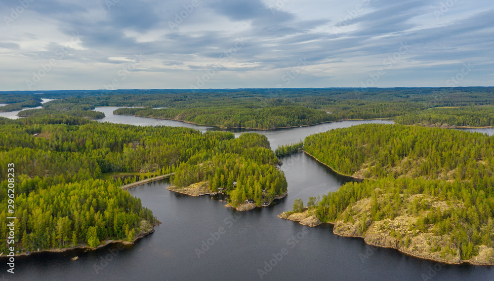 Aerial view of of small islands on a blue lake Saimaa. Landscape with drone. Blue lakes, islands and green forests from above on a cloudy summer morning. Lake landscape in Finland.