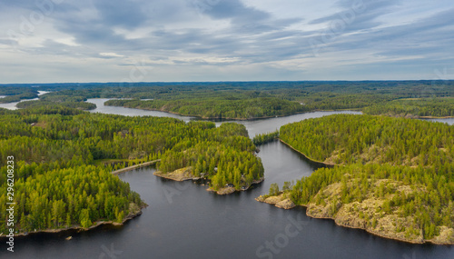 Aerial view of of small islands on a blue lake Saimaa. Landscape with drone. Blue lakes  islands and green forests from above on a cloudy summer morning. Lake landscape in Finland.