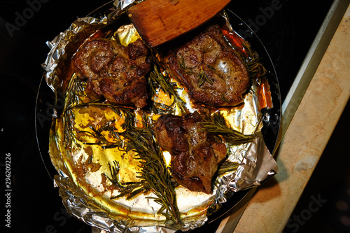 Roasted meat with rosemary on a foil photo