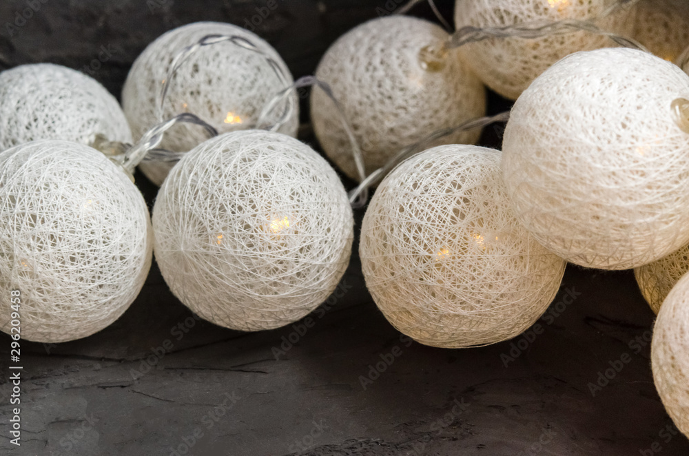 Garland of Christmas lights with round white lanterns on a gray dark background. Garland of Christmas lights with round white lanterns on a gray dark background.