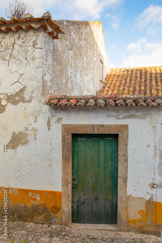 Green painted wooden door and rustic white house exterior with terra cotta roof © Isabelle
