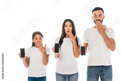 surprised parents and kid holding smartphones with blank screens isolated on white