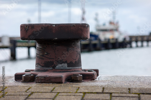 Bollards for mooring ships on the quay wall in a harbor on the German Baltic Sea island of Ruegen. In the background a ship out of focus with beautiful bokeh.