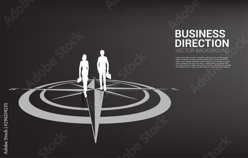Silhouette of businessman and businesswoman walk forward on center of compass on floor .Concept of career path and business direction