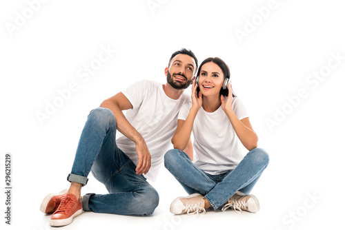 happy woman listening music in headphones near bearded man isolated on white