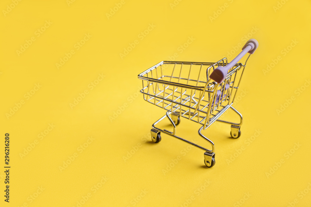 Supermarket trolley on the yellow background Supermarket trolley on the yellow background