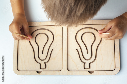 Montessori Games for Child Development Games for Child Development wooden toy. Board for interhemispheric development of the brain. Children's hands close-up. Spiral circle circle photo