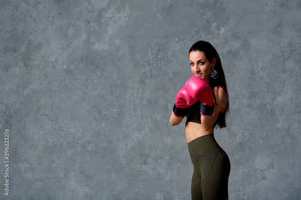 Beautiful athletic girl posing in pink boxing gloves on a gray background. Copy space. Concept sport, fight, goal achievement. Beautiful athletic girl posing in pink boxing gloves on a gray background. Copy space. Concept sport, fight, goal achievement.