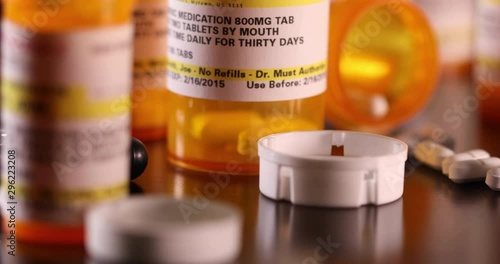 Slow Panning of Non-proprietary Medicine Bottles, Pills and Stethoscope on Dark Wood Surface.